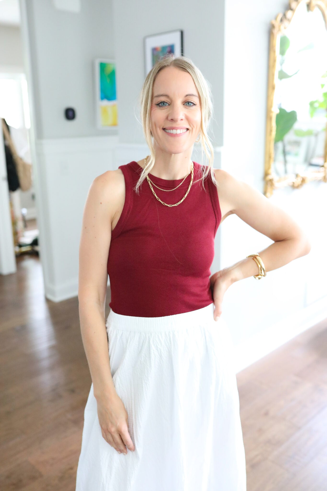 Jen wearing a dark red ribbed tank tucked into a white maxi A-line skirt, styled with gold accessories for a polished warm-weather look.