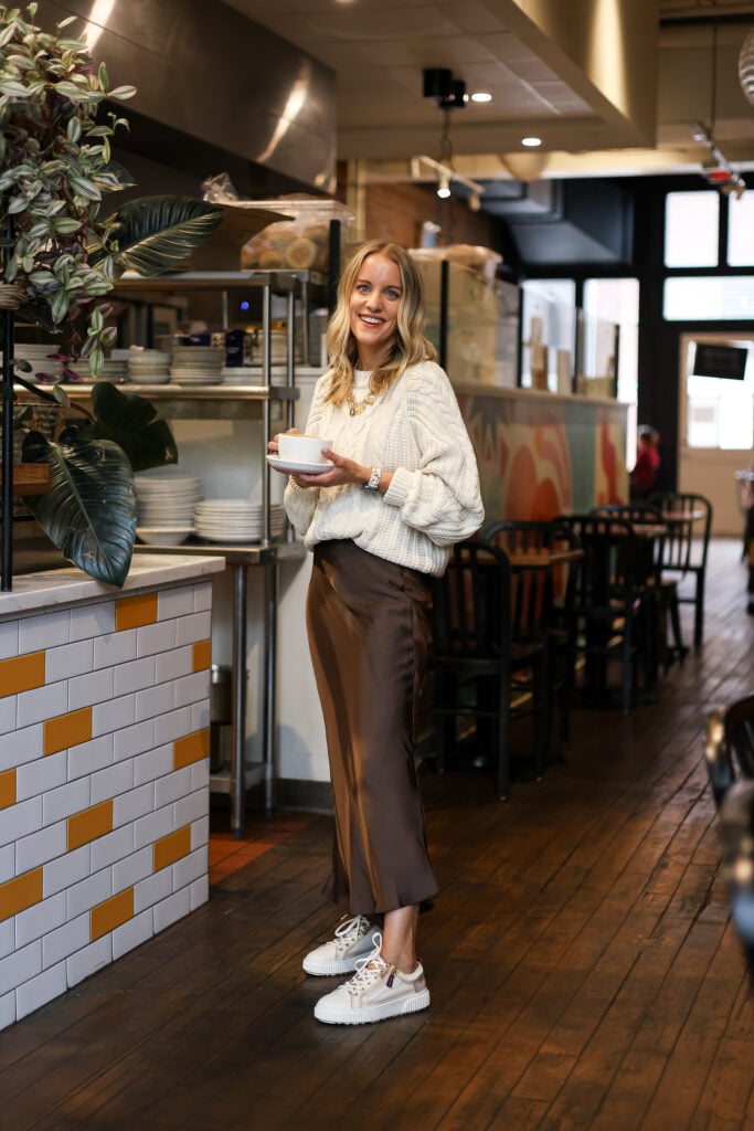 Woman in brown skirt, sweater and sneakers