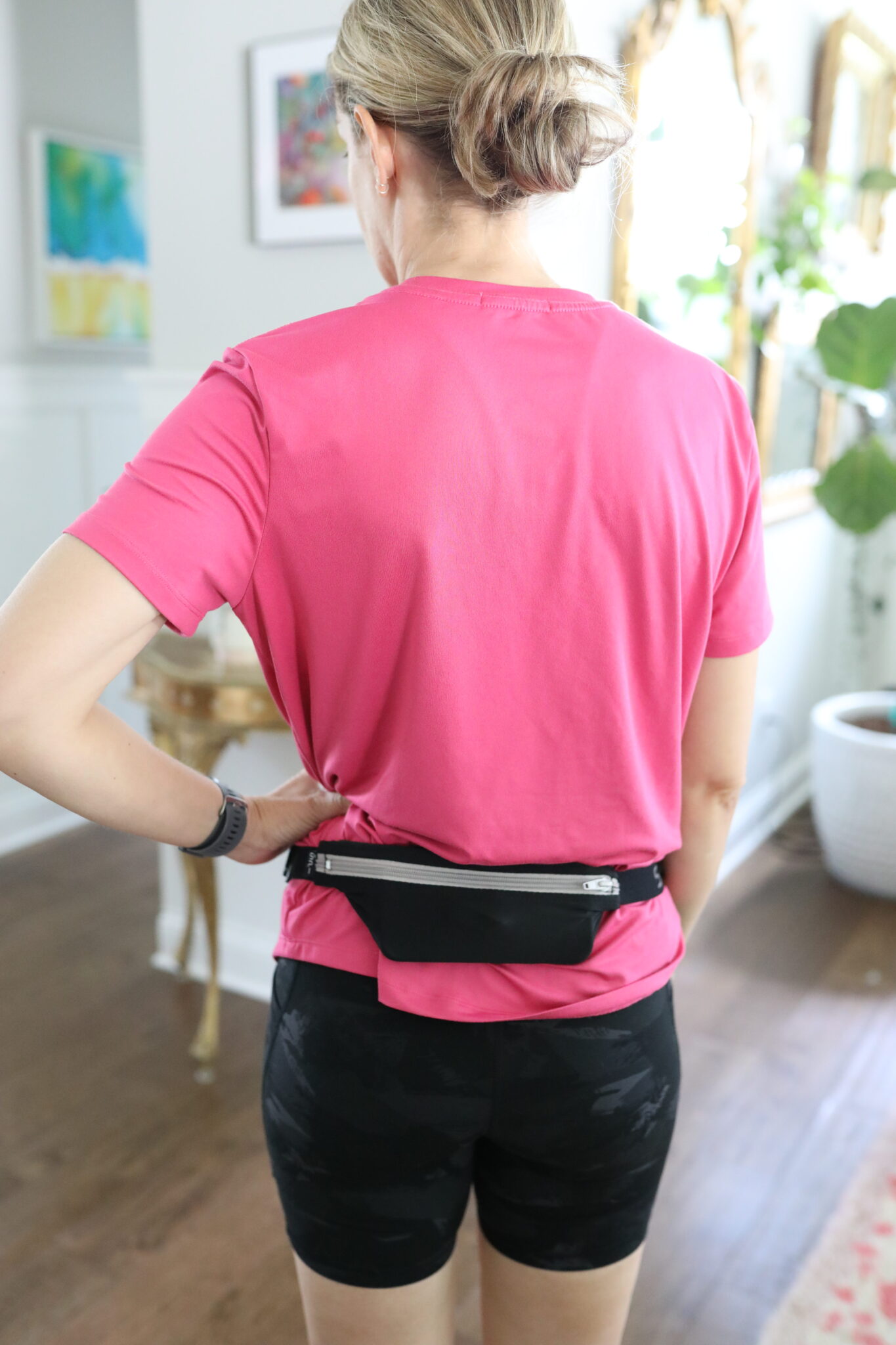 Back view of Jen wearing a hot pink Pinspark athletic shirt tucked into black camo Colorfulkoala biker shorts. Styled with a black waist belt bag and an Apple Watch.