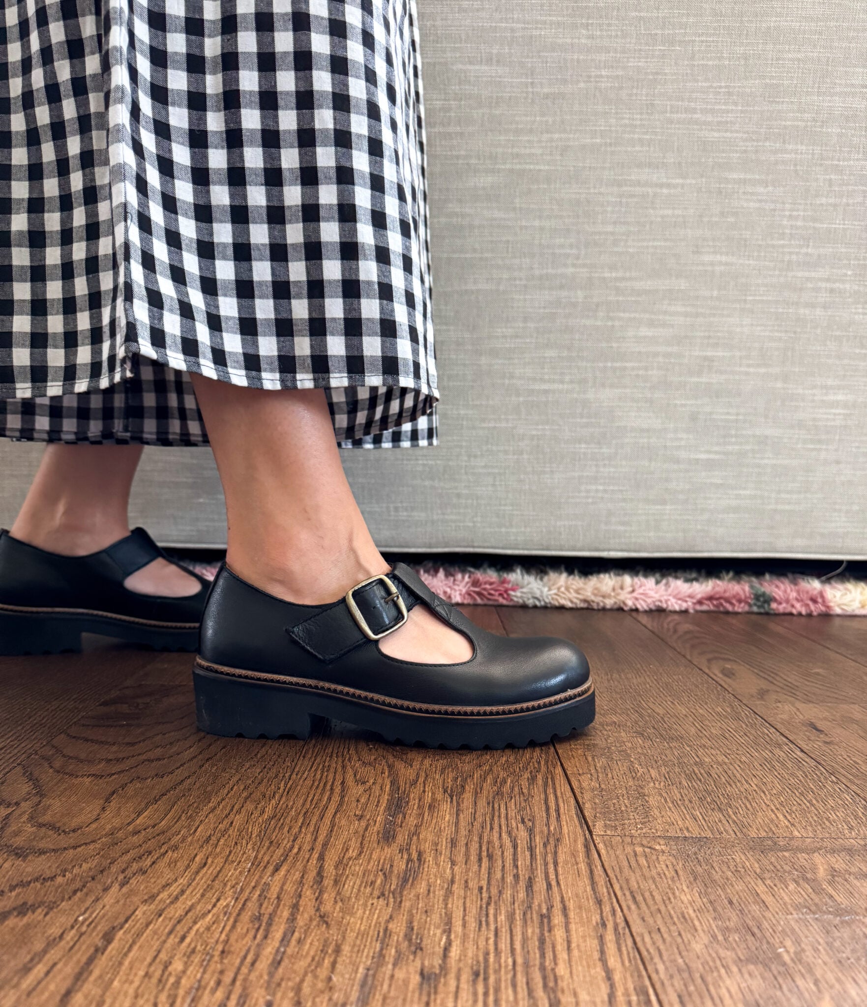 en Paisley of Paisley and Sparrow wearing black chunky Mary Jane loafers with buckle detail styled with black-and-white gingham cropped pants, trendy womenās fall shoes from Schuler Shoes.