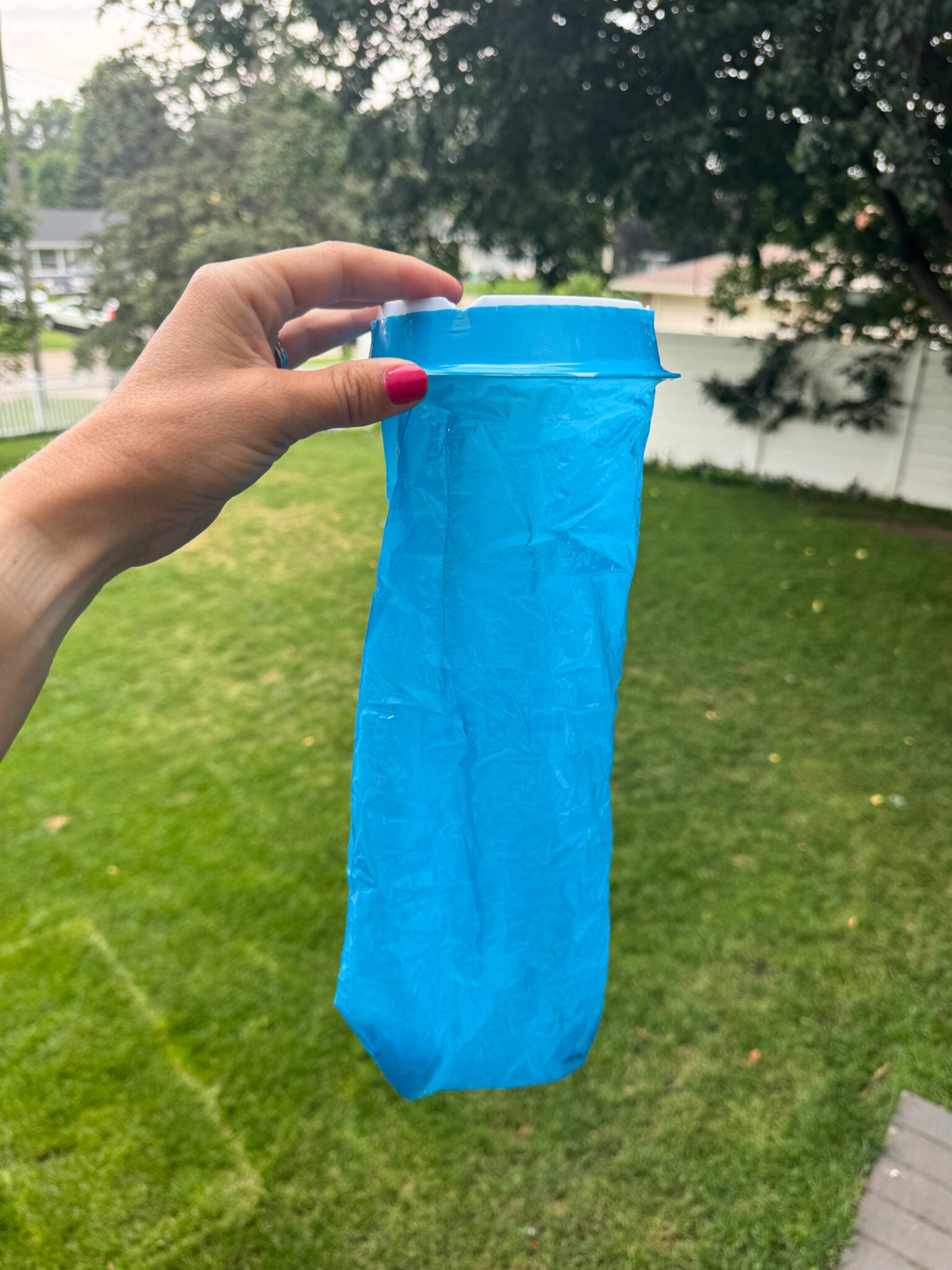 Blue disposable travel sickness bag held in a hand outdoors