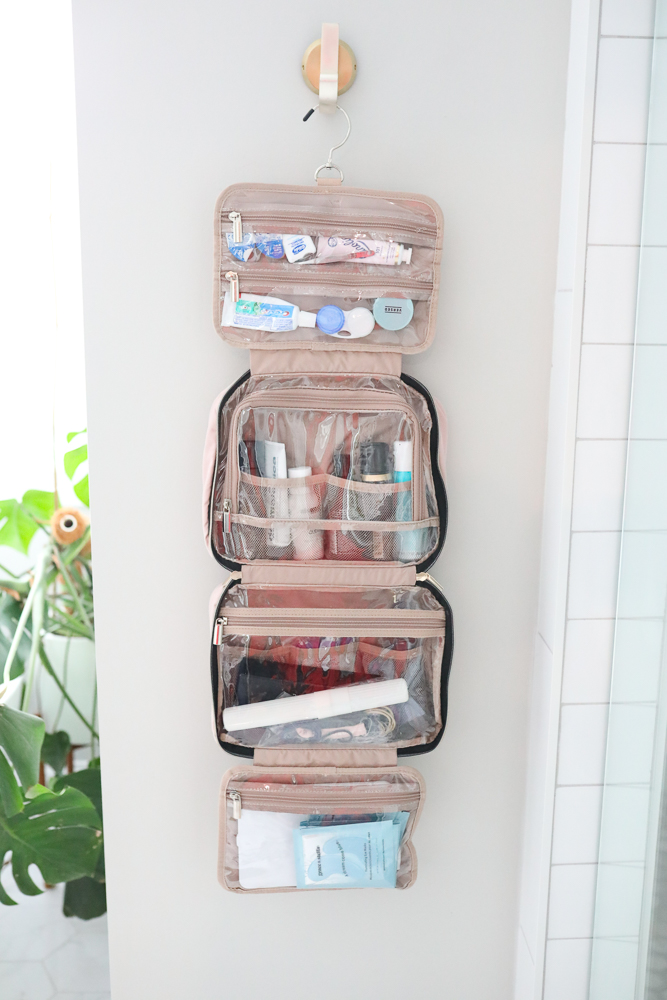 Hanging toiletry bag with clear compartments filled with travel size products