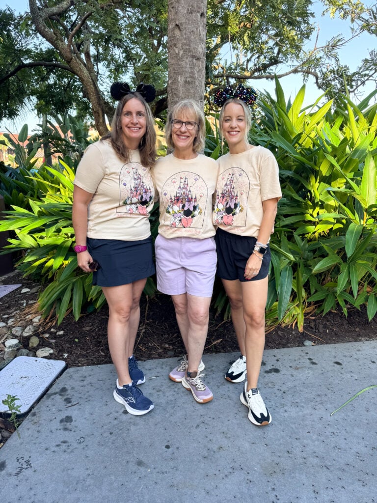 Three women wearing matching Minnie Mouse and Daisy Duck shirts