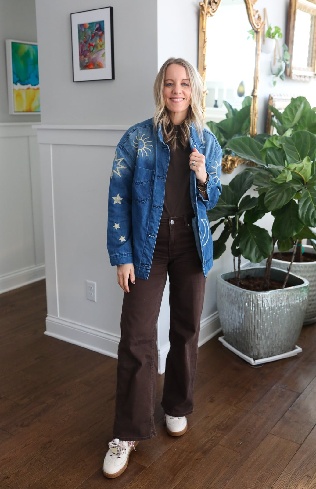 Woman in brown pants, brown shirt and denim jacket.