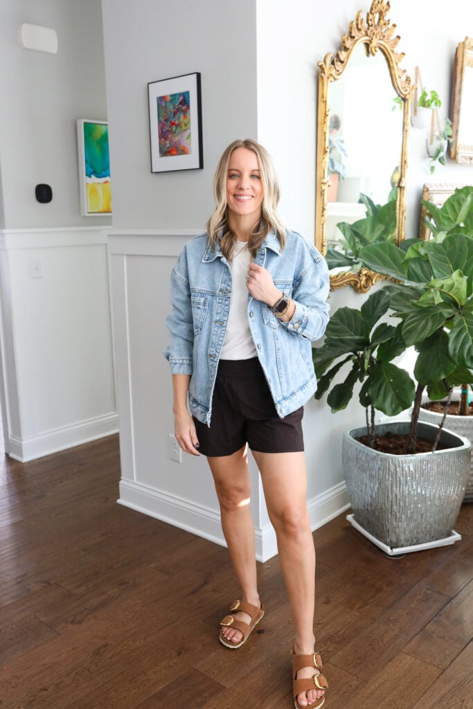Woman in athletic shorts, tank and denim jacket.