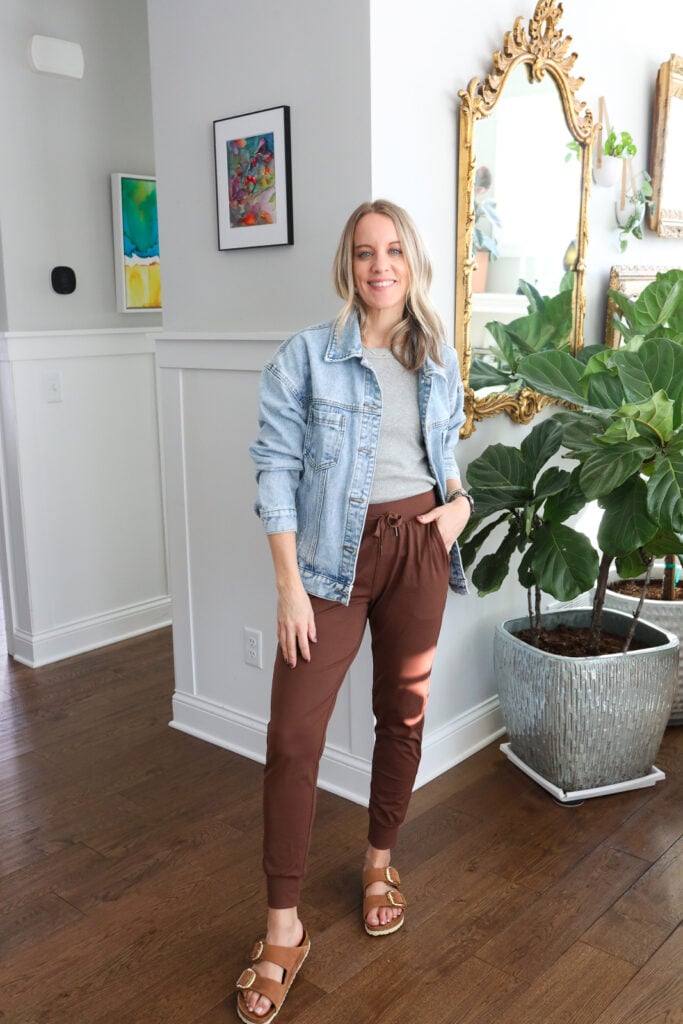 Woman in joggers, tank and denim jacket with sandals.
