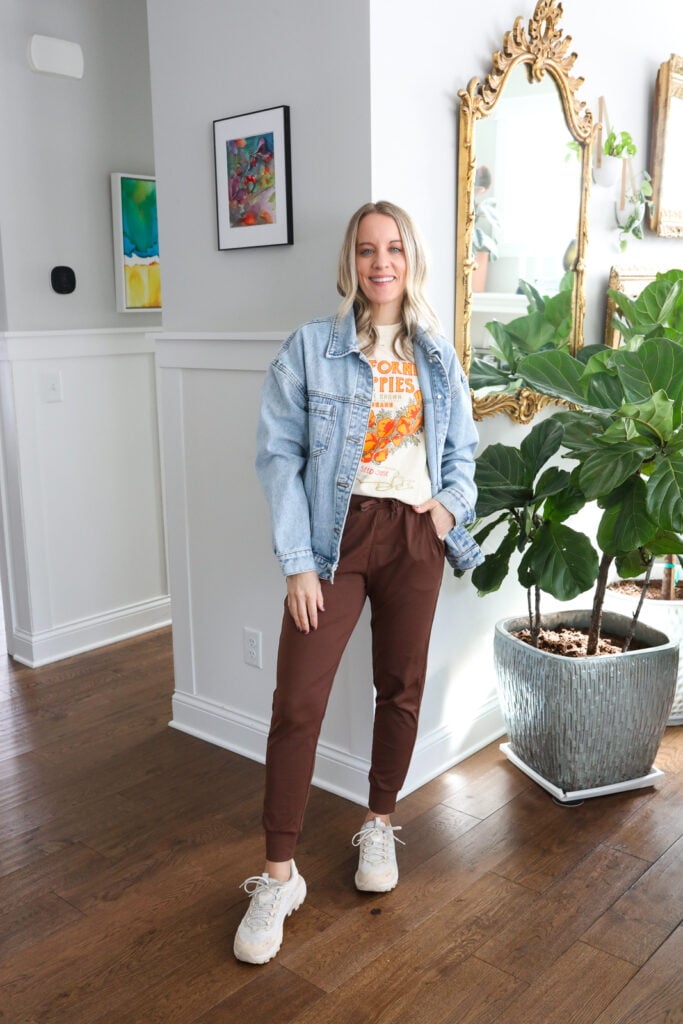 Woman in brown joggers, graphic tee and denim jacket.